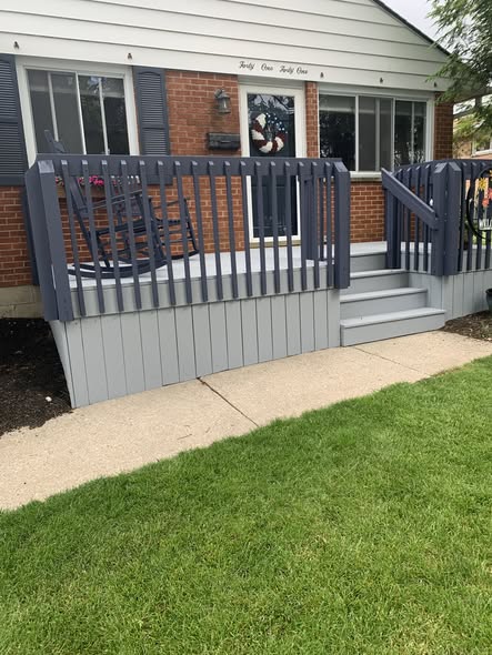 Rebuilt gray deck with navy railing on a brick ranch home