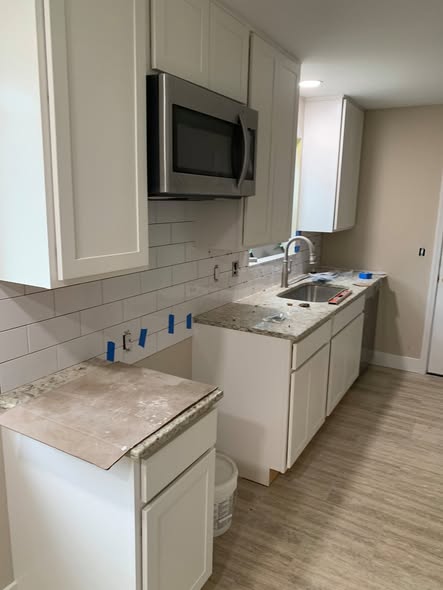 Kitchen remodel in progress with new white cabinets and subway tile