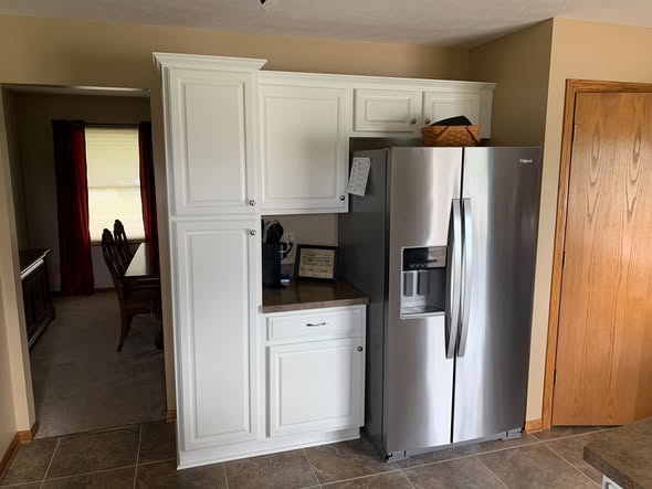 Painted white cabinetry beside stainless steel refrigerator